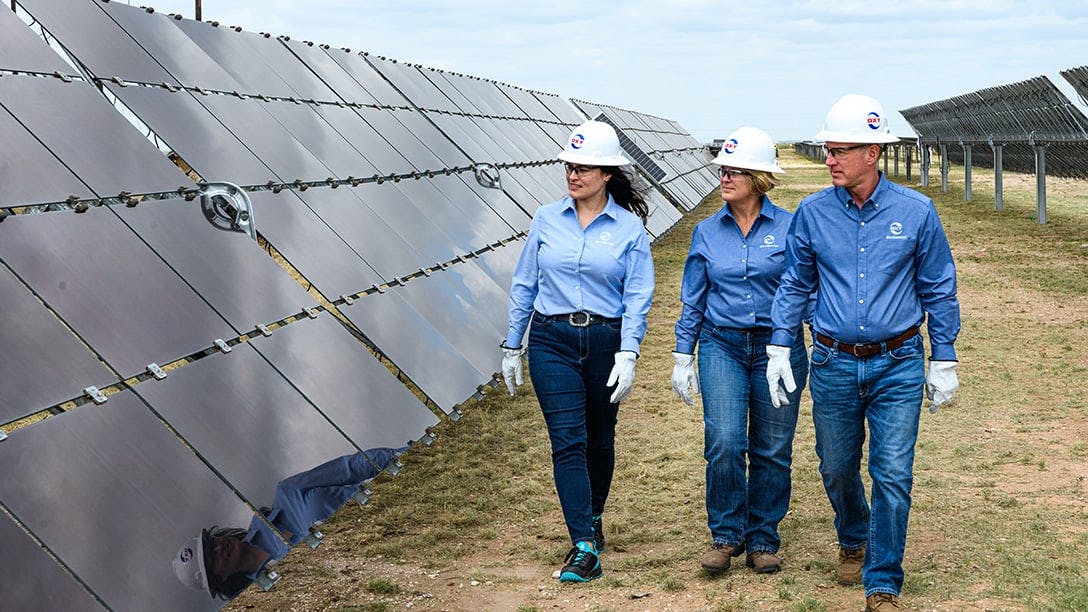 Three employees walking along solar panels at GoldSmith facility