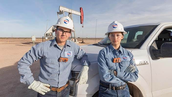 Two Oxy employees leaning on work truck in field